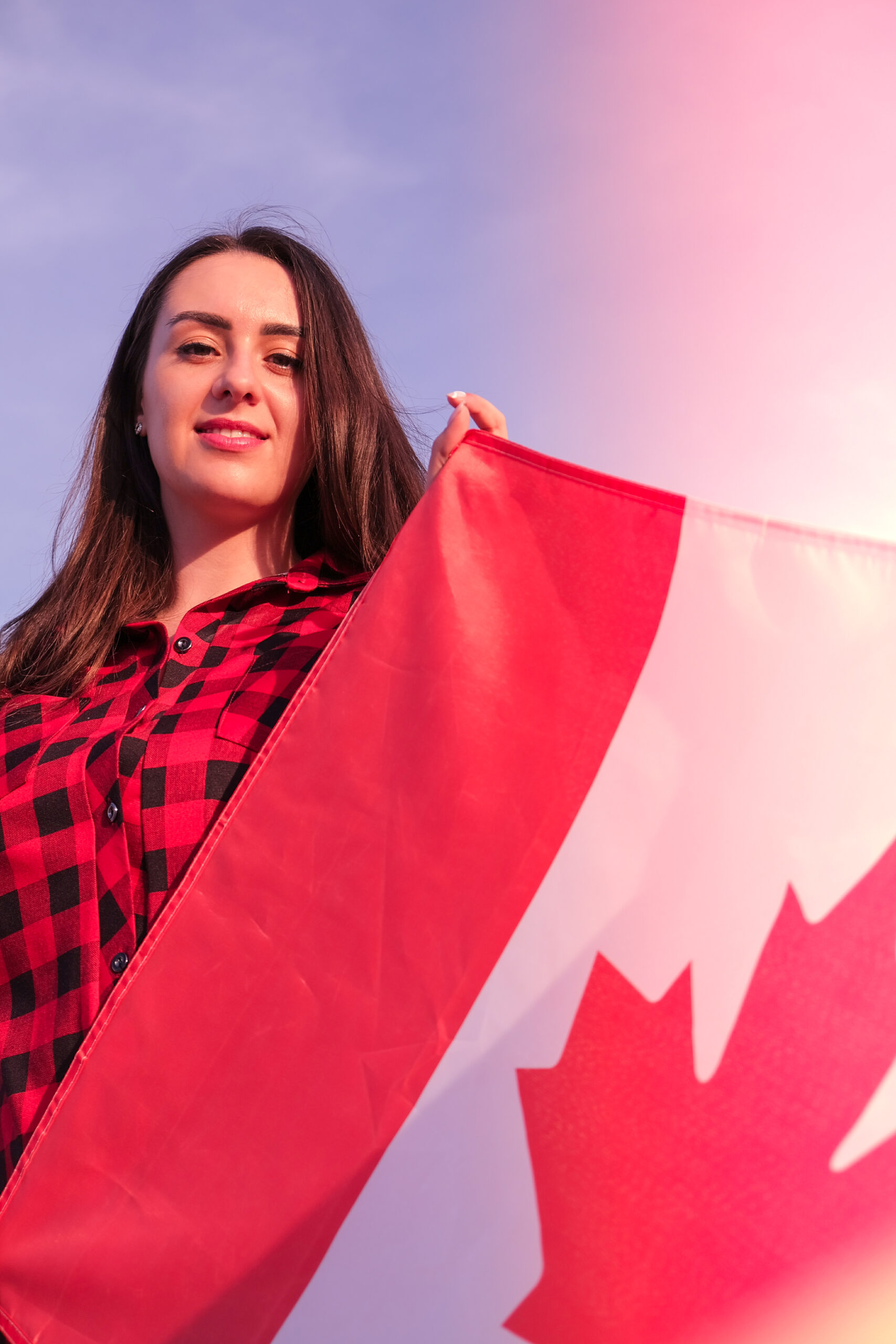 Young millennial brunette woman holding The National Flag of Canada. Canadian Flag or the Maple Leaf. Tourist traveler or patriotism. Immigrant in a free country. Independence day 1th july